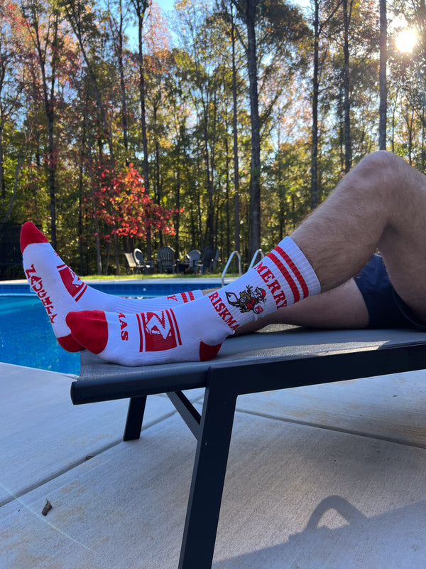 Riskmas socks on a pair of hairy legs laying poolside