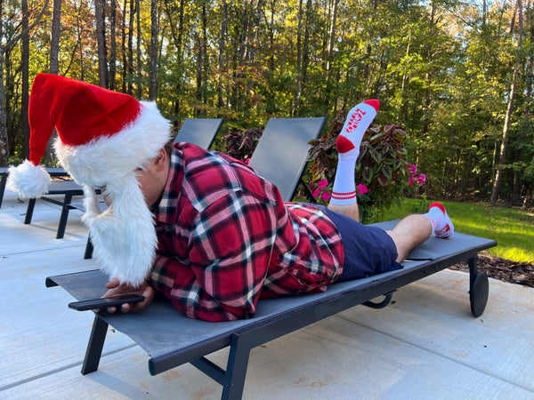 Santa wearing Riskmas socks laying poolside scrolling his phone