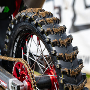 Close up of a Hawkstone paddle tire on a dirt bike with a little bit of mud on each paddle